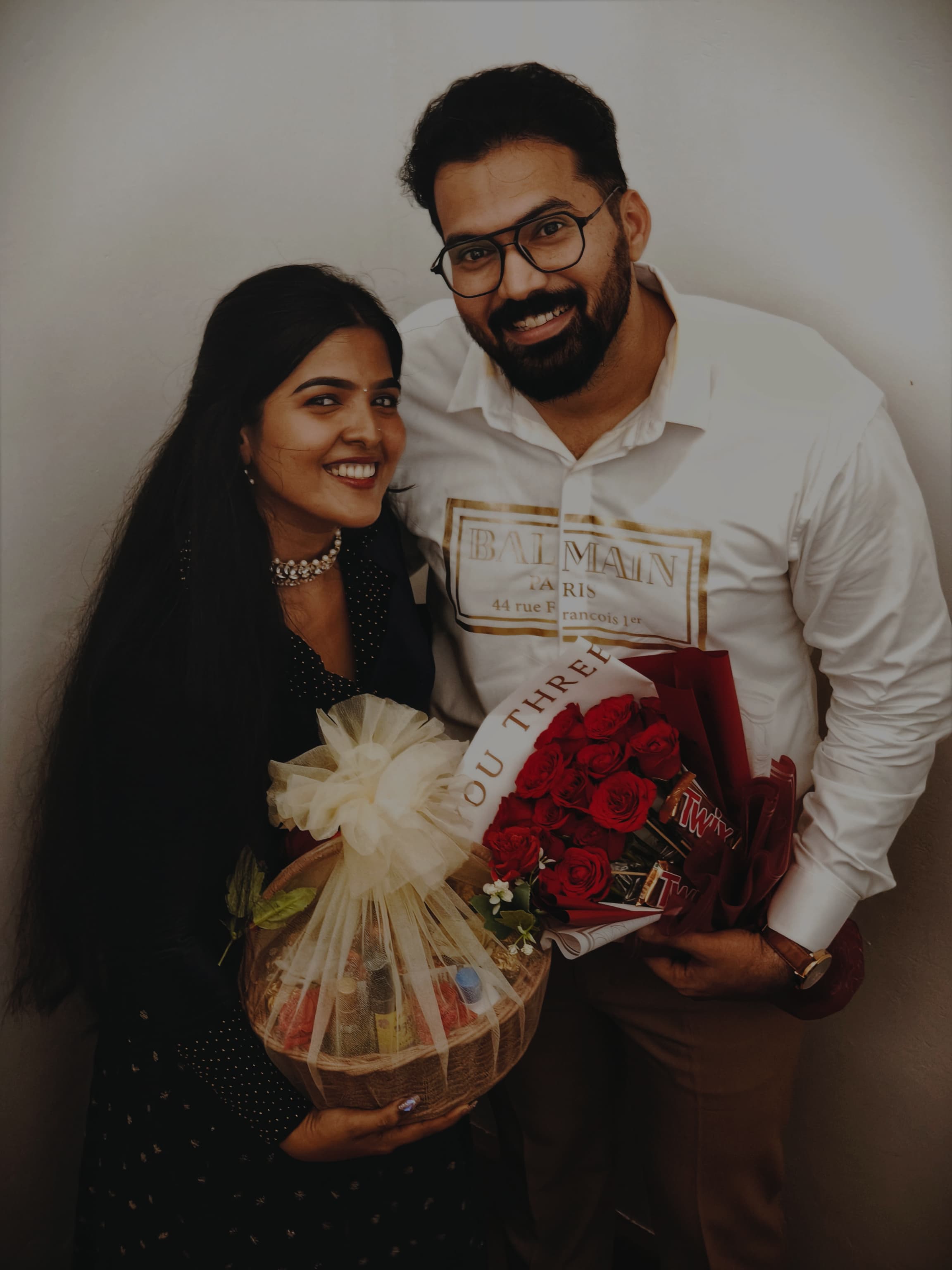 Couple posing with roses and a gift basket